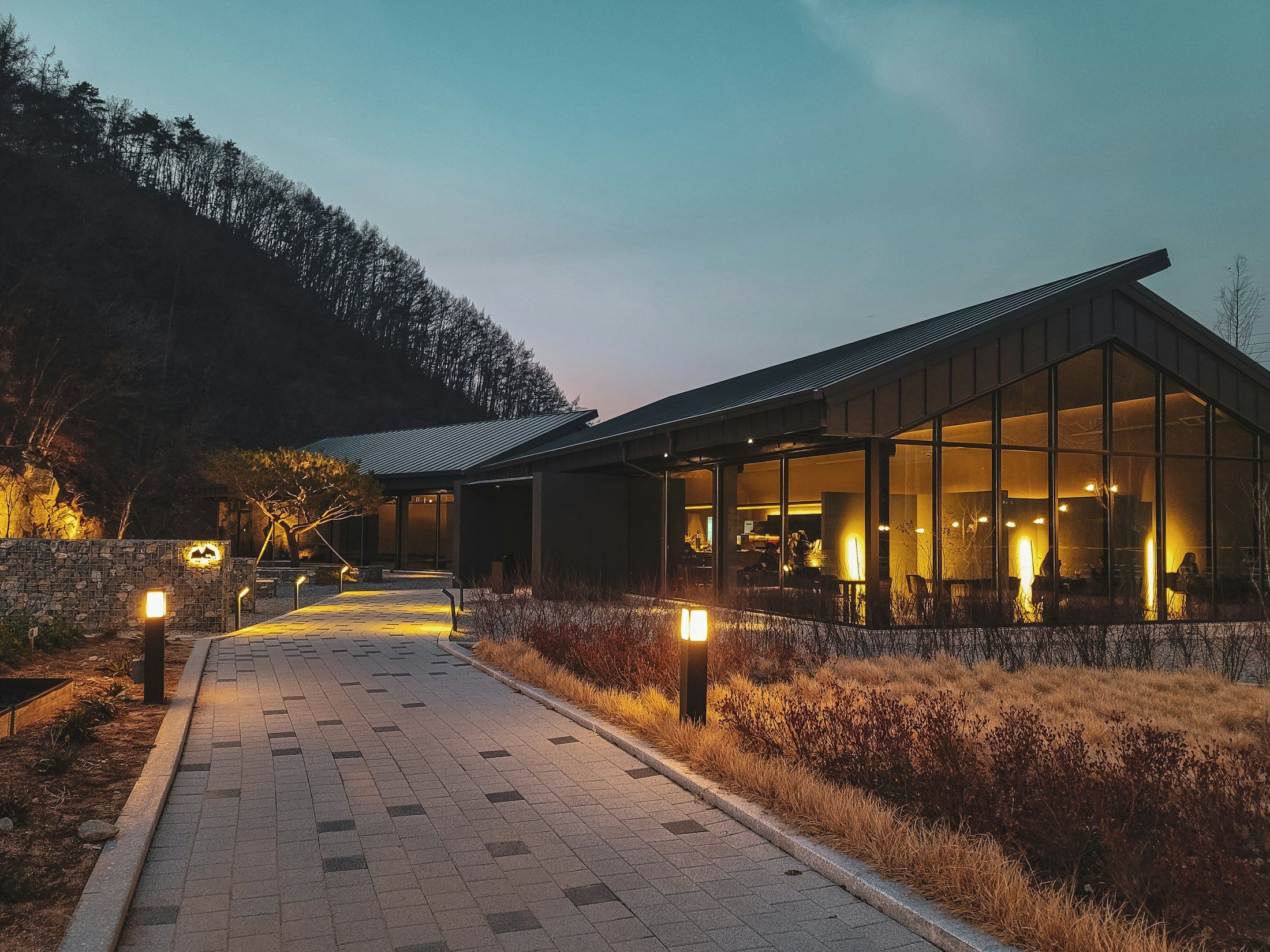 Glass pavilion lit from within at dusk